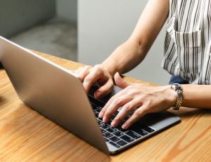 Image of a woman typing on a laptop computer.