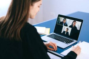 Image of a person in business attire attending a conference call meeting on their laptop.