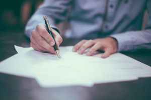 A man in a violet dress shirt edits a printed article with a pen. 