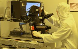 A semi-conductor operator working at a lab station in protective gear. 