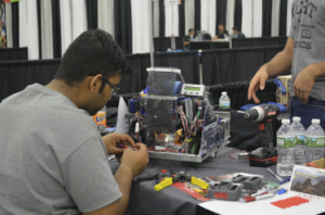 A college student examines the inner workings of an electronic device. 