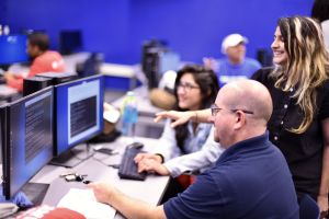 Two people look at two computer monitors