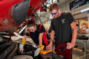 Two student technicians from the CAAT Center look over a car. Photo taken from the latest Impacts book