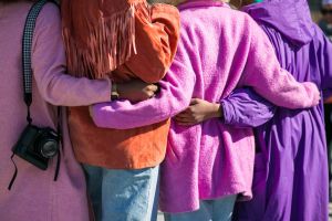 A photo of four people interlocking arms, from the back