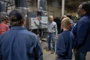 Adjunct Instructor Brad Fitzgerald demonstrates concepts he taught in class while students tour Fleet Laboratories.